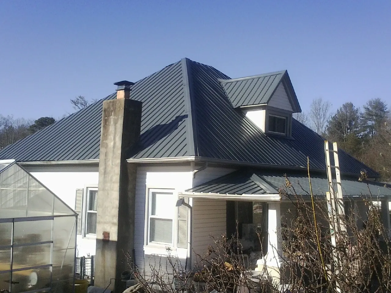 Dark blue standing seam metal roof on a white farmhouse with dormer — Slate & Tile Roof Repair by Roofing Brothers in Defiance
