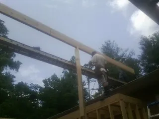 Carpenter setting a ridge beam over a new addition frame — Ice Dam Removal by Roofing Brothers in Defiance