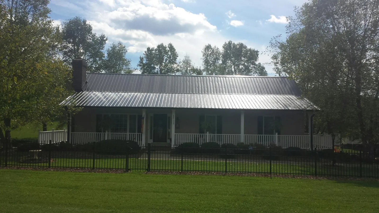 Gray metal roof on a brick ranch with a full width front porch — Gutter Guard Installation work by our crew in Defiance