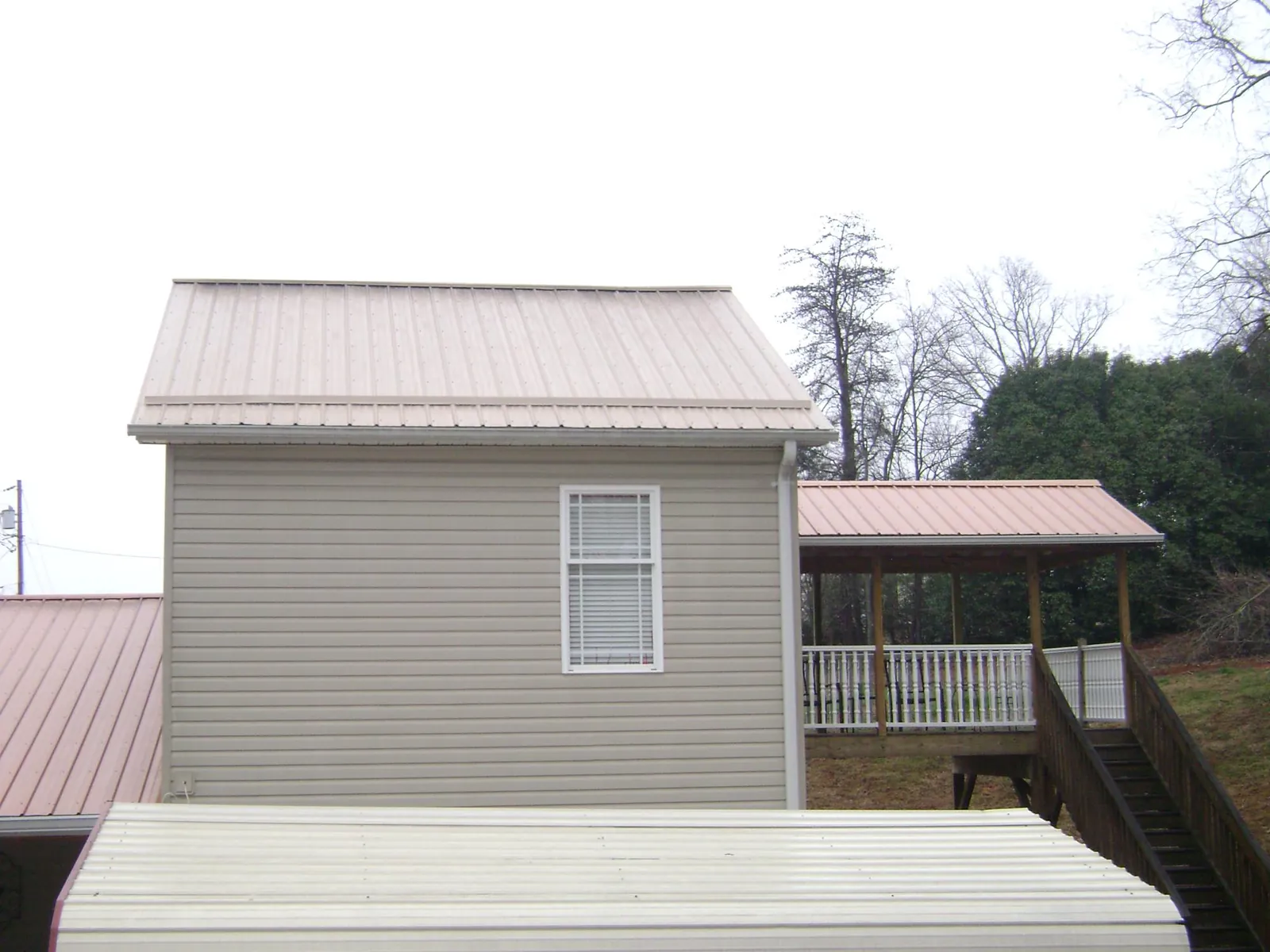 Tan metal roofs on a two story addition and attached porch, from a Roof Replacement job in Defiance
