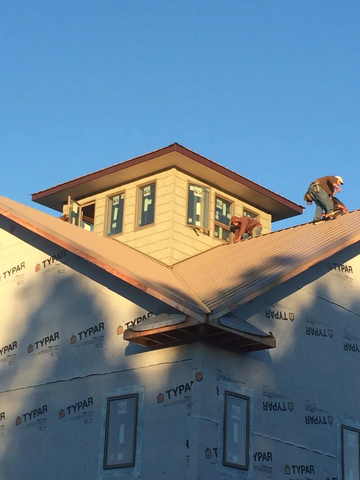 Roofers working around a rooftop cupola on a new metal roof at sunset — Roof Waterproofing in Defiance by Roofing Brothers